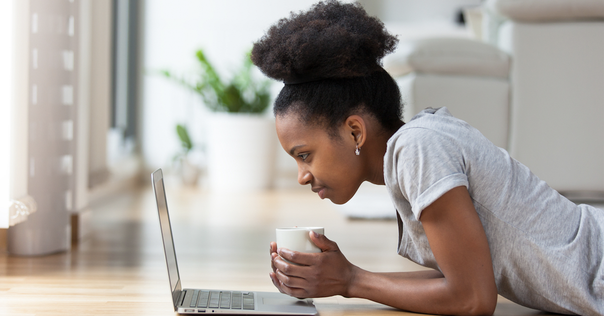 young-girl-holding-a-mug-and-working-on-her-laptop