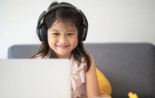 smiling-girl-wearing-headphones-and-looking-at-laptop-screen